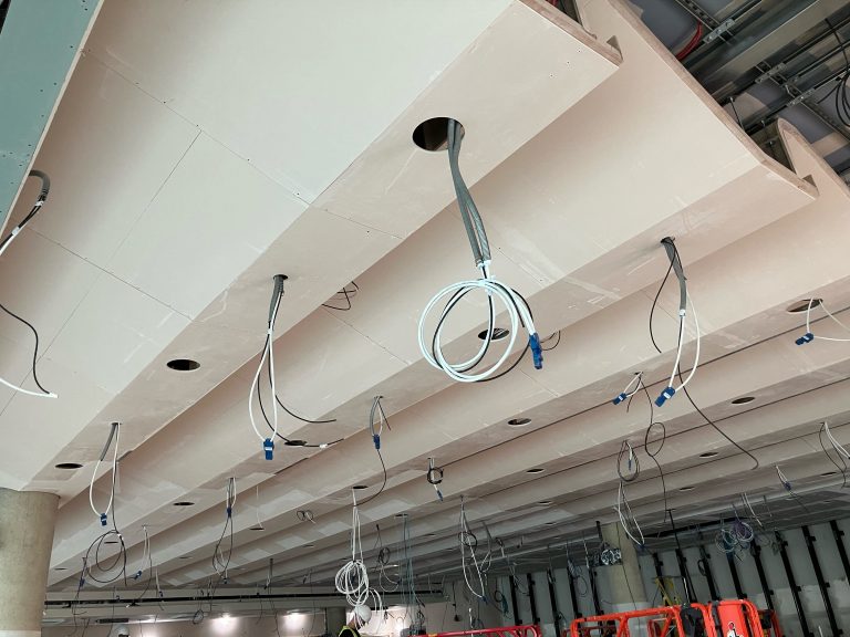 Underside view of offsite-manufactured acoustic ceiling cassettes installed at Cambridge auditorium, with pre-cut service openings