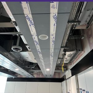 Plasterboard ceiling foils being installed at Manchester Airport with protective film still on the panels and building services visible above