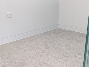 Shadow gap skirting close-up showing the recessed shadow line where a white wall meets a tiled floor